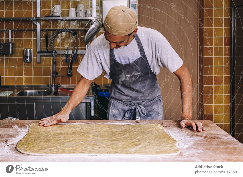 Cook preparing dough for baking baker man cook raw process prepare flour male bakehouse dirty bakery apron table food work recipe job fresh occupation culinary