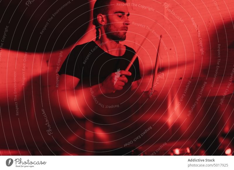 Man playing drums music drummer band drumsticks rehearsing rehearsal room man studio redness guy instrument smiling neon light young musician musical sound