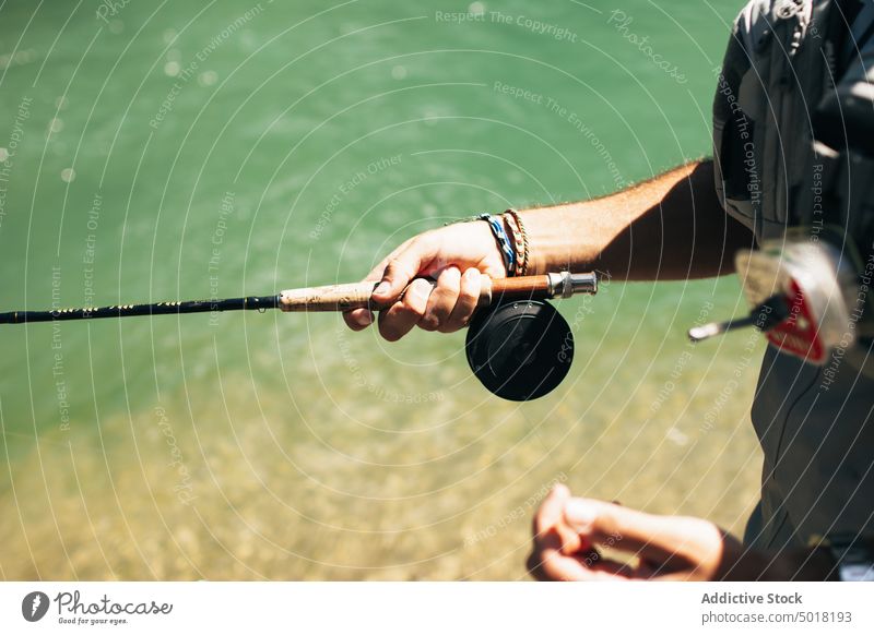 Fisherman man throwing fishing rod into a mountain river - a
