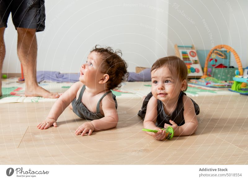 Cute happy twin babies lying on floor and plying with toys children sibling baby play adorable smile similar father home together cute toddler childhood parent