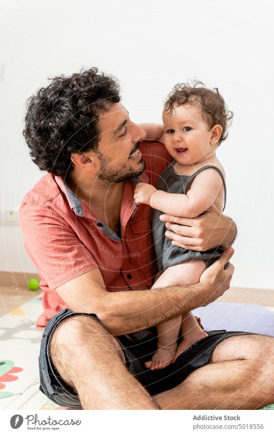 Joyful young father with baby playing together with toys sitting on mat man happy excited close love cheerful joy adorable infant multiracial multiethnic