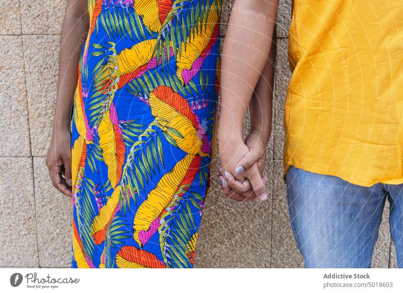 Crop ethnic couple holding hands on street love colorful summer relationship touch together city romantic boyfriend girlfriend fondness close urban wall