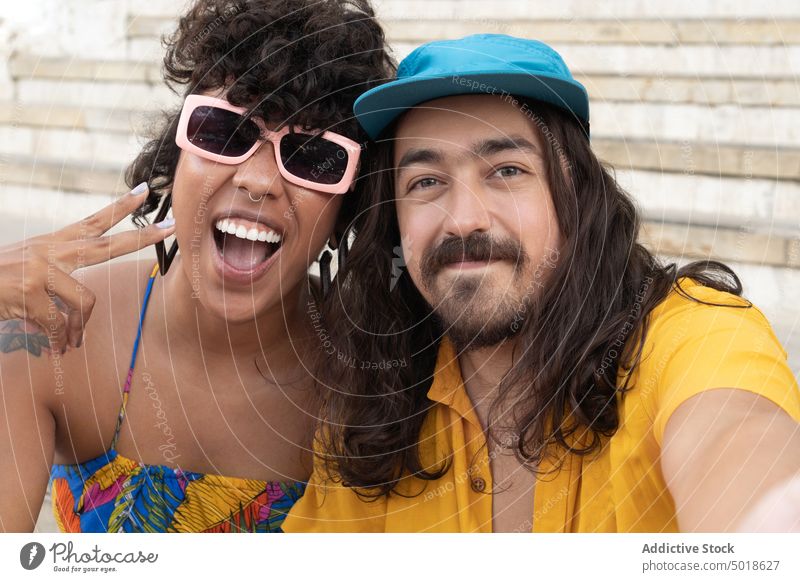 Cool ethnic couple embracing and taking selfie hipster self portrait cool colorful gesture having fun v sign embrace together relationship moment memory