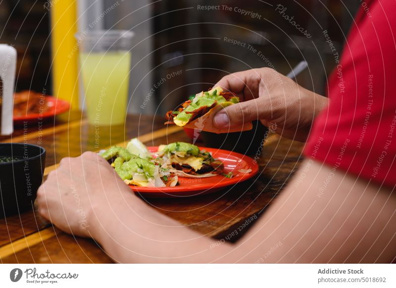 Crop person eating delicious taco at table street food mexican food lunch meal dish dinner restaurant tortilla culture tradition glass beverage refreshment