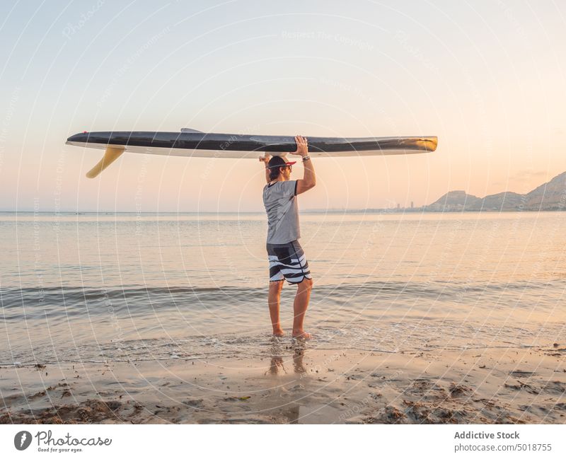 Man holding surfboard over head and looking along man seaside summer vacation water beach sport ocean surfer lifestyle leisure recreation active sand hobby