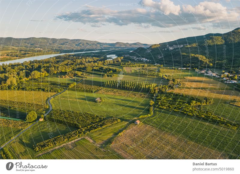 Aerial view of the Rhone River. In the vicinity of the town of Le Pouzin - France. During sunset. Trees that cast a shadow over the surrounding fields. Farmland during sunset. Tree shadows