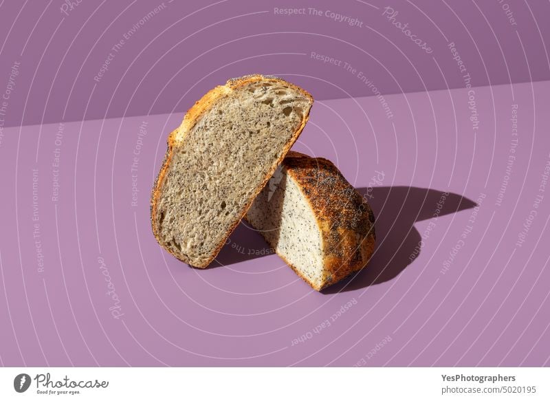 Bread with poppy seeds sliced in half, isolated on a purple background arranged artisan baked bakery bread bright carbs close-up color crust cuisine delicious