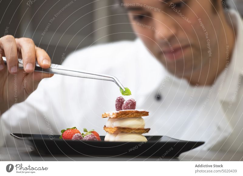 Professional chef serving dessert professional dish focused fancy plate raspberry serious table man white young adult food cuisine restaurant kitchen cook meal