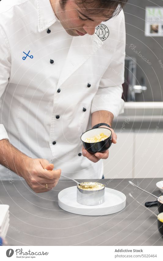 Male chef cooking food on table with containers in kitchen man professional process restaurant male adult uniform metal prepare job dish work concentrate recipe