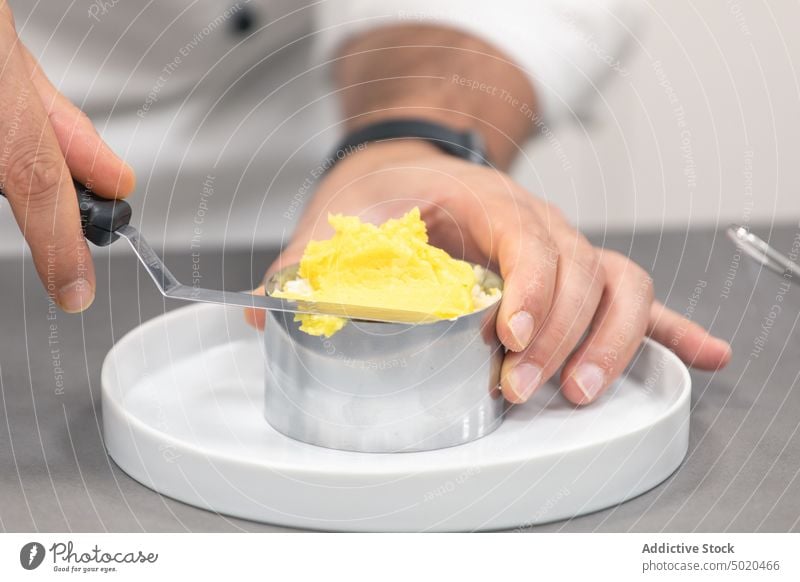 Unrecognizable chef spreading butter on baking form on plate man cook spatula utensil process kitchen table ingredient male prepare recipe professional uniform
