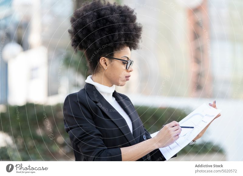 Serious female architect with draft of building in city woman blueprint paper plan businesswoman smart street ethnic black african american suit urban