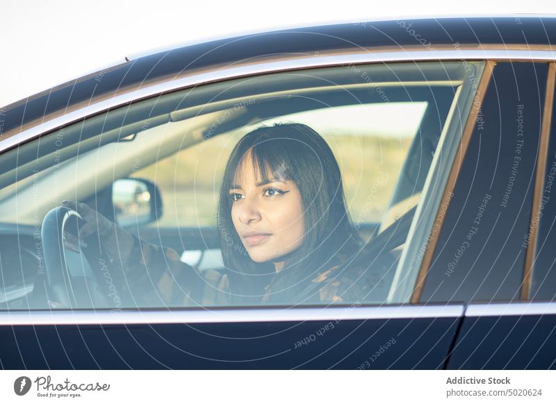 Attentive young ethnic lady driving car in countryside woman drive attentive vehicle driver road road trip transport calm style female latin american dark hair
