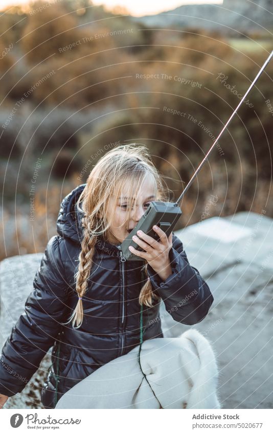 beautiful young girl using a walkie-talkie on forest child male communication playground playing green portrait blue radio cute fun childhood outdoors playful