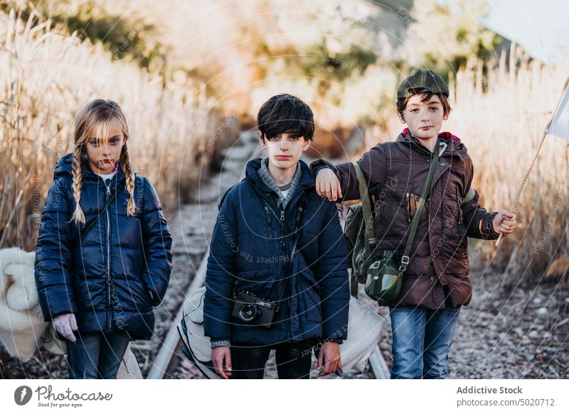 Group of three children standing in the woods kids hiking siblings discovery camping young friends group of kids excited activity log family caucasian lifestyle