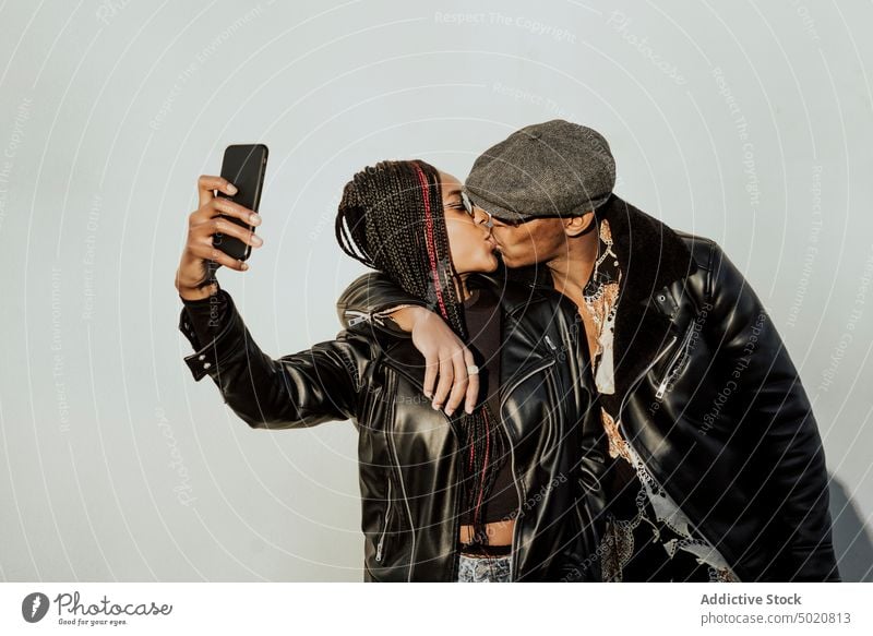 Black couple kissing and taking selfie wall embracing black young street city smartphone woman together love lifestyle leisure exterior building hugging
