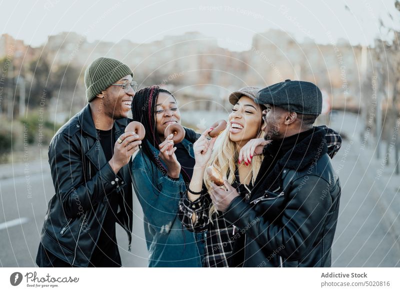 Black friends eating donuts on street black city leisure lifestyle smiling together young men women tasty delicious yummy doughnuts african american ethnicity