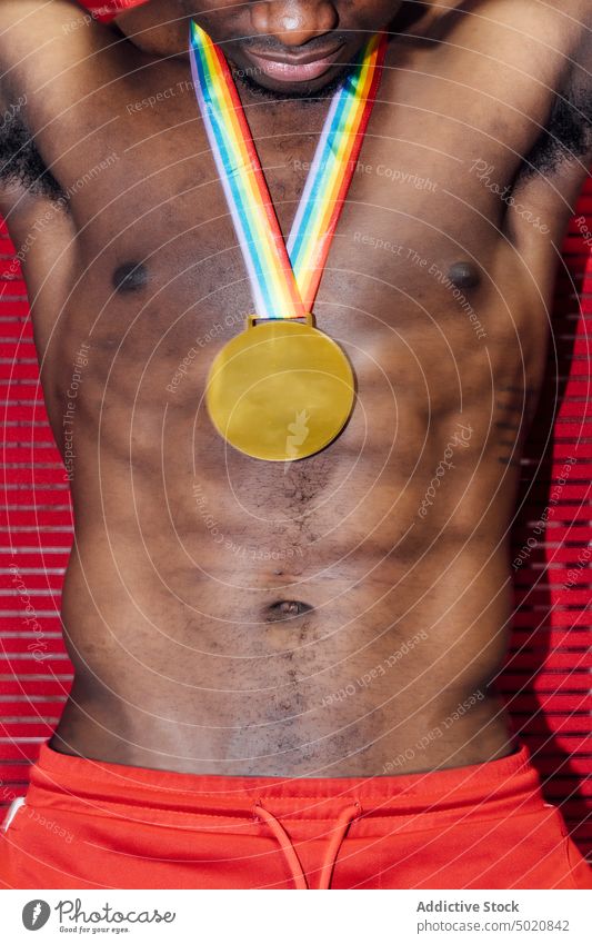 Crop black man with fake medal shirtless party nightlife confident wall bright red male muscular fit strong power success strength body torso nightclub guy