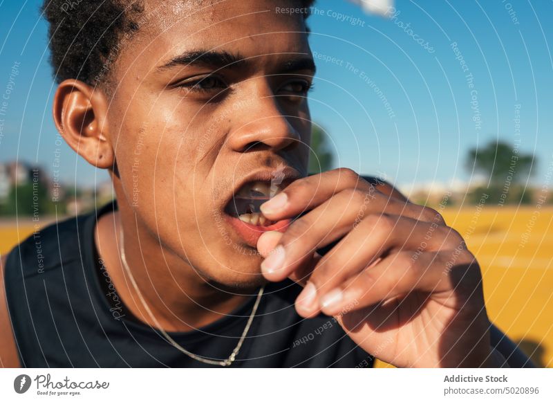 Black athlete putting mouthguard in mouth sport player season serious equipment face protection practice uniform youth activity athletic head competition safety