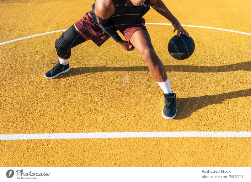 Active black athlete dribbling ball in playground sportsman game player kicking playing sportswear activity field male powerful fit lap stadium professional