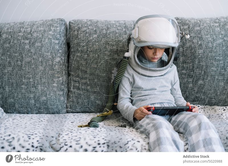 Adorable kid with a real astronaut uniform playing with a video game console background boy child childhood concept costume creation diy handmade helmet