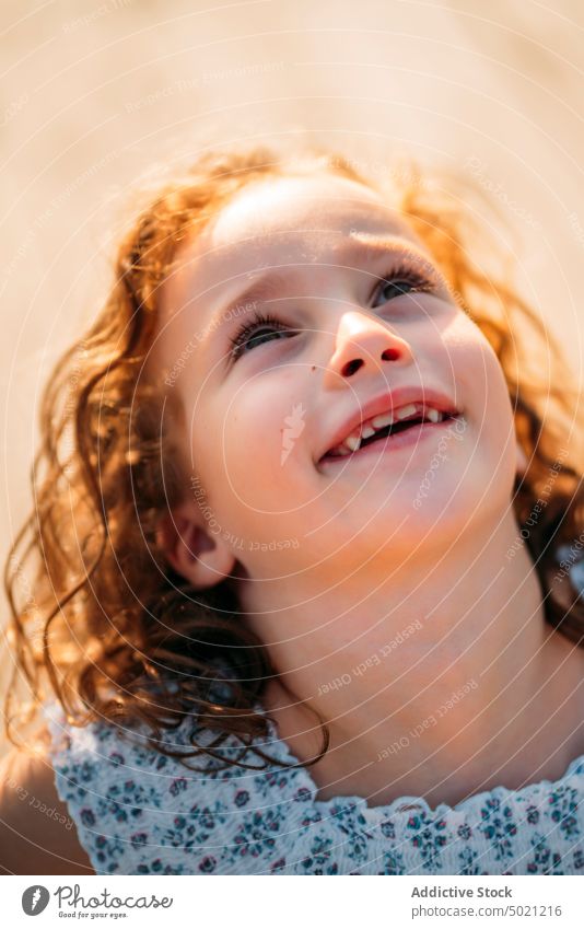 Excited girl looking up kid cheerful ginger sunny daytime child little smiling excited fun innocence carefree red curly hair cute adorable sweet lovely charming