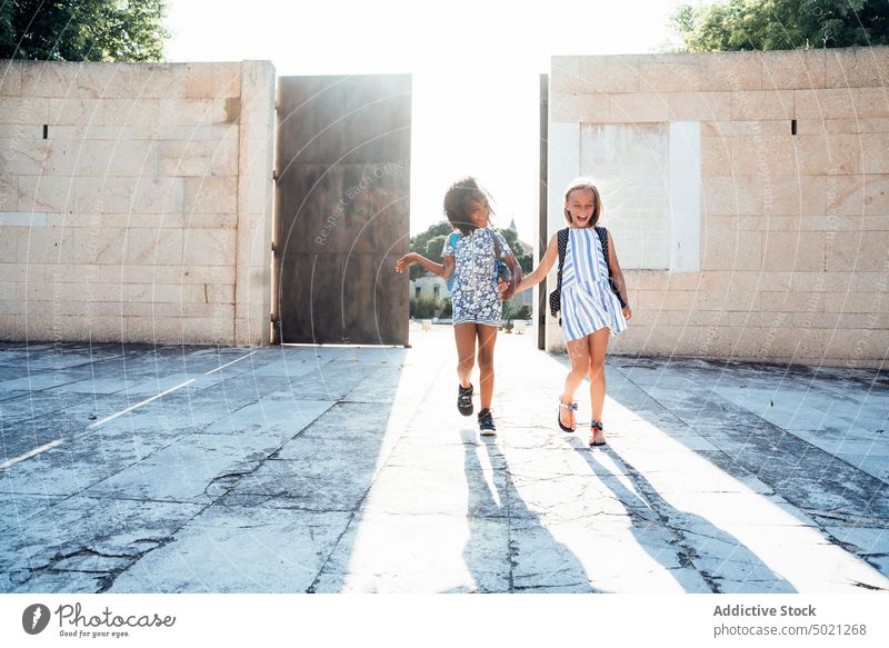 Laughing African American girl walking with friend on street in best friend bonding happy children multiethnic african american together diversity multiracial