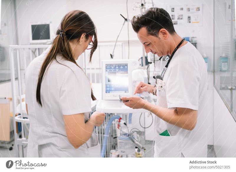 Couple of doctors controlling work of medical device in hospital woman couple equipment modern adjusting treatment healthcare cure digital technology carefully