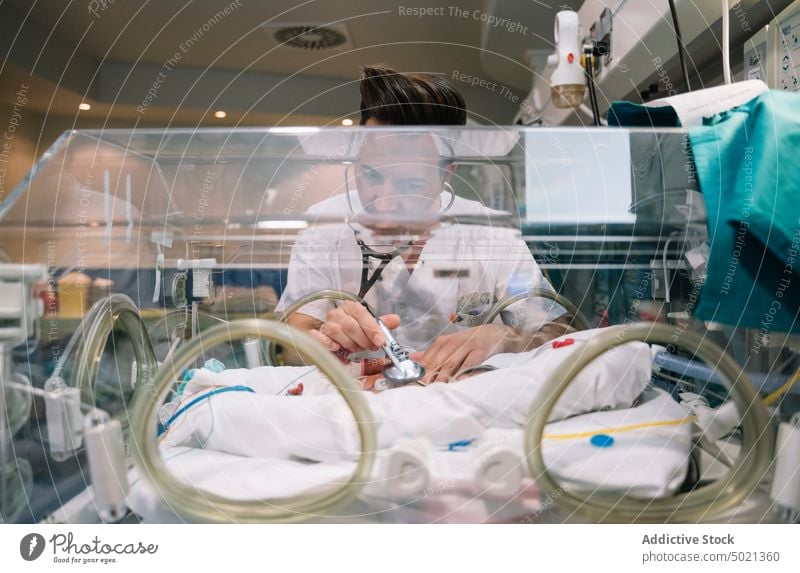 Doctor listening newborn baby in incubator doctor medical pediatrician hospital treatment neonatologist care child man innocent healthcare carefully cure