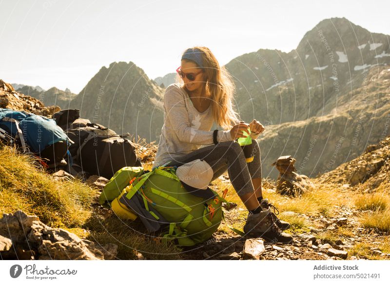 Female hiker with water resting in mountains woman smile break backpack sunny daytime pyrenees female relax happy sit cheerful travel vacation trip summer
