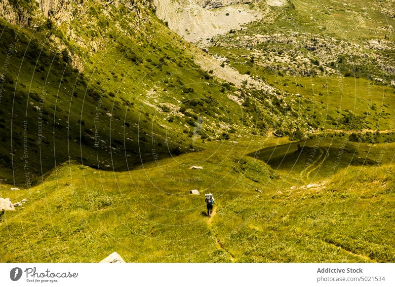 Anonymous man tourist walking on grassy path in mountains valley explore nature landscape ridge highland pyrenees male range scenic slope travel hike tourism