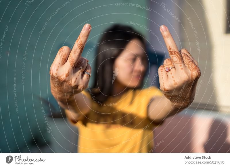 Asian woman showing middle fingers with mehndi rude fuck gesture street urban city female ethnic asian india art creative paint decorate stand casual style sign