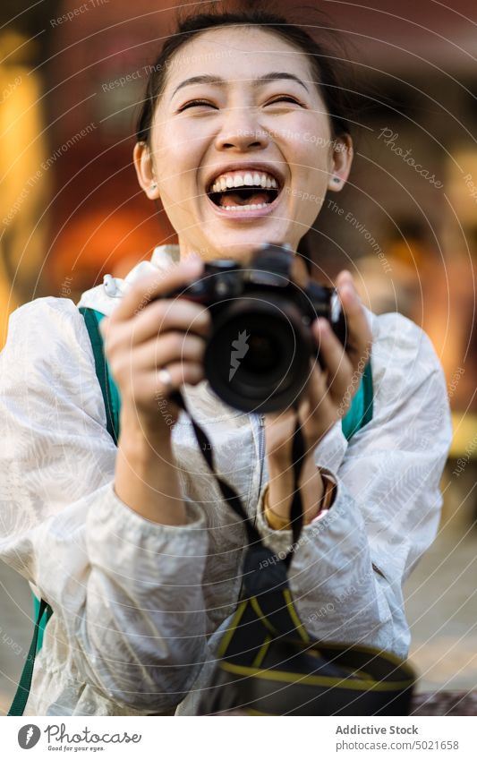Happy ethnic tourist with photo camera woman take photo laugh street happy memory india female asian eyes closed photographer casual trip excited shoot