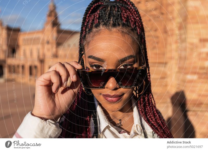 Black woman standing on square in city braid hairstyle smile stroll sunny weekend cheerful female black ethnic african american plaza de espana seville spain