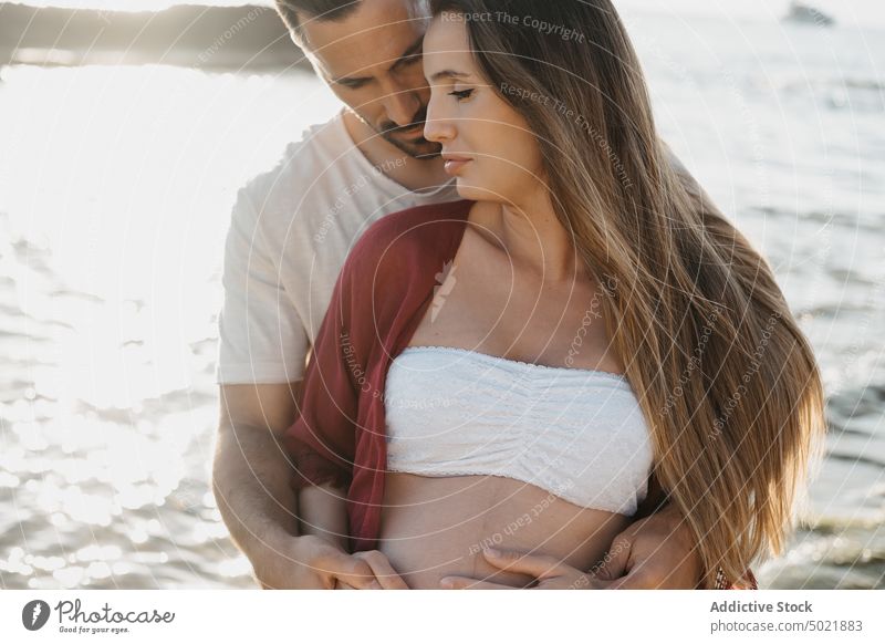 Pregnant couple standing near sea sunrise pregnancy embrace together love coast relationship man thoughtful woman hug shore pregnant countryside tender morning