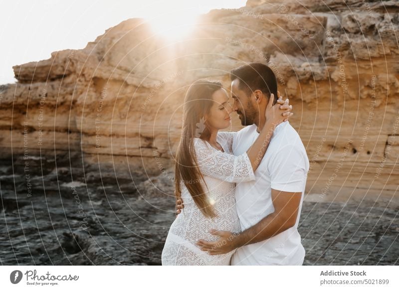 Happy pregnant couple hugging in nature pregnancy morning cliff love together relationship happy man woman cheerful smile embrace relax summer rest belly