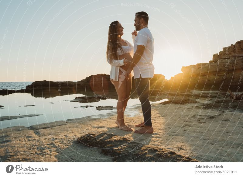 Pregnant couple standing near sea at sunrise pregnancy together love coast relationship holding hands man woman shore pregnant countryside tender morning mother