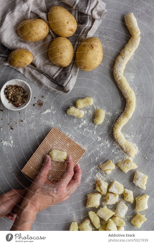 Crop person cooking potato gnocchi for lunch dough press board ribbed pasta table kitchen pepper flour prepare food ingredient process fresh recipe cuisine raw