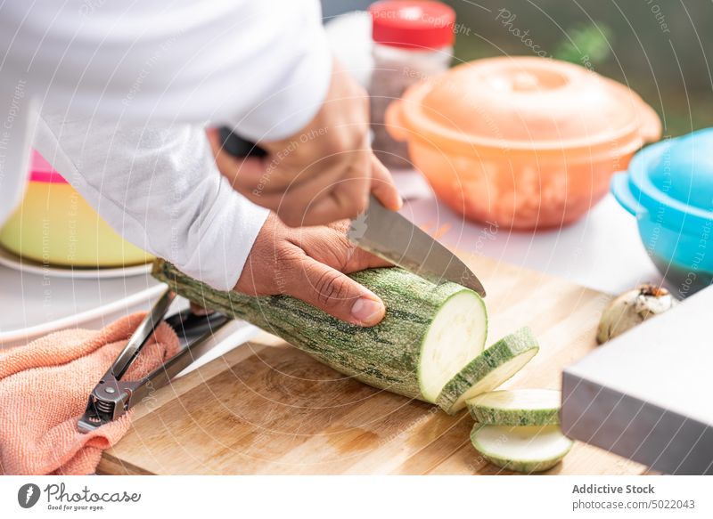 Crop man slicing ripe zucchini with knife on cutting board cook prepare kitchen food vegetable fresh chop slice culinary ingredient meal recipe nutrition