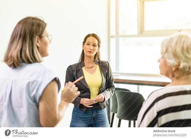 Colleagues standing and talking in hallway in office women project coworker colleague listen discuss communicate workplace female hispanic ethnic costa rica