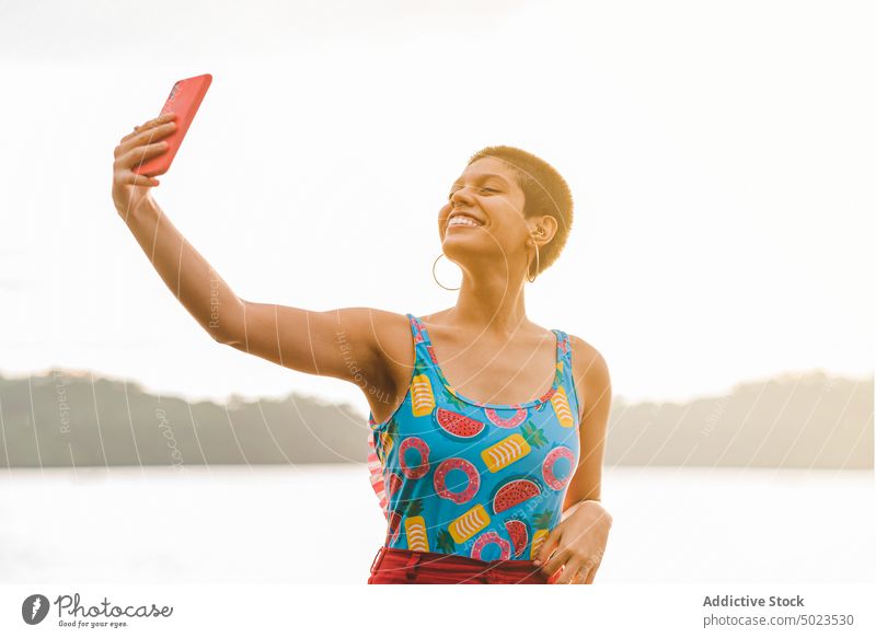Happy woman taking selfie on beach happy summer smartphone cheerful smile vacation carefree colorful female young millennial enjoy gadget mobile using lifestyle
