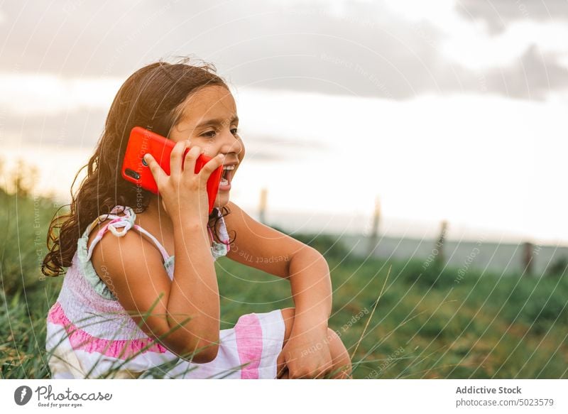 Hispanic girl speaking on smartphone in field sunset happy rest weekend grass summer cheerful joy positive countryside gadget device nature talk lifestyle smile