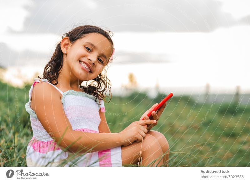 Hispanic girl speaking on smartphone in field sunset happy rest weekend grass summer cheerful joy positive countryside gadget device nature talk lifestyle smile