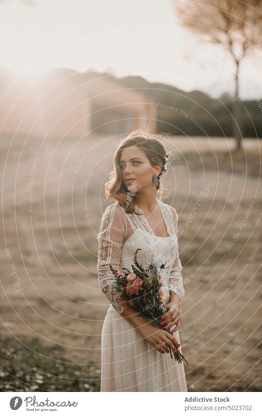 Charming woman in dress with bouquet on field wedding lady hand hair bunch flower meadow sunny young attractive charming passionate marriage party celebration