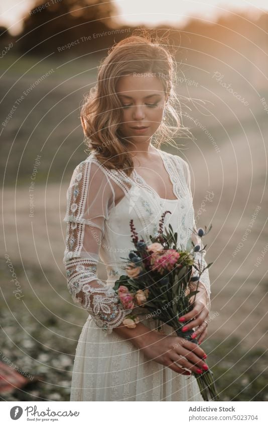 Charming woman in dress with bouquet on field wedding lady hand hair bunch flower meadow sunny young attractive charming passionate marriage party celebration