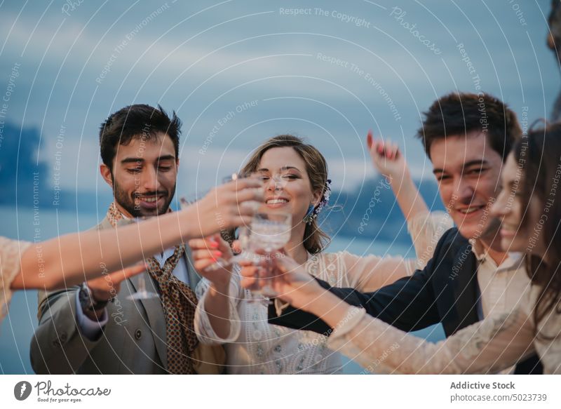 Young people in evening wear clanging glasses with drinks toast man woman beverage young happy smiling party celebration shindig fun attractive cheerful