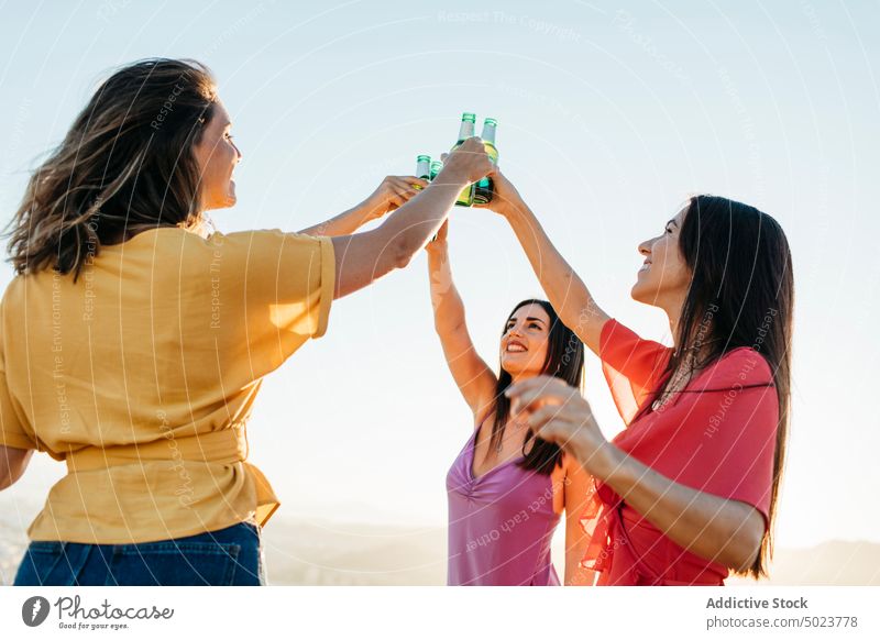 Happy friends clinking bottles of beer women toast joy girlfriend fun cheers group gather female drink alcohol happy beverage together glass celebrate cheerful