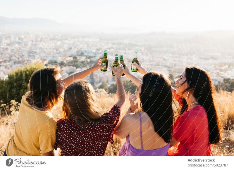 Happy friends clinking bottles of beer women toast joy girlfriend fun cheers group gather female drink alcohol happy beverage together sit glass celebrate