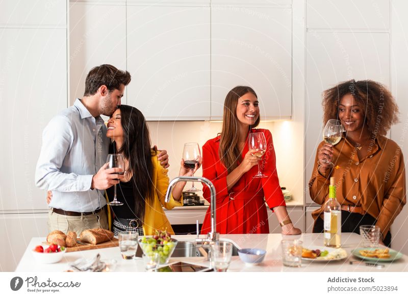 Young friends drinking wine at home together party alcohol celebrate festive gather kitchen beverage laugh cheerful casual young table diverse multiracial