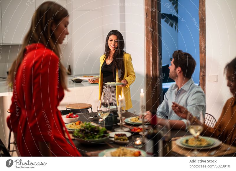 Multiethnic friends enjoying dinner at home together party celebrate dish festive event gather meal holiday chill meeting cheerful casual young table diverse