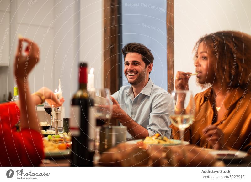 Multiethnic friends enjoying dinner at home together party celebrate dish festive event gather meal holiday chill meeting cheerful casual young table diverse